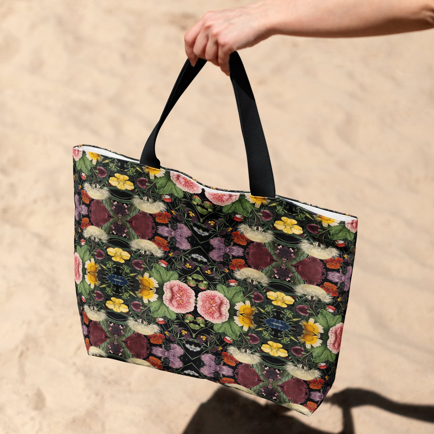 Floral-patterned tote bag held by a hand on a sandy background