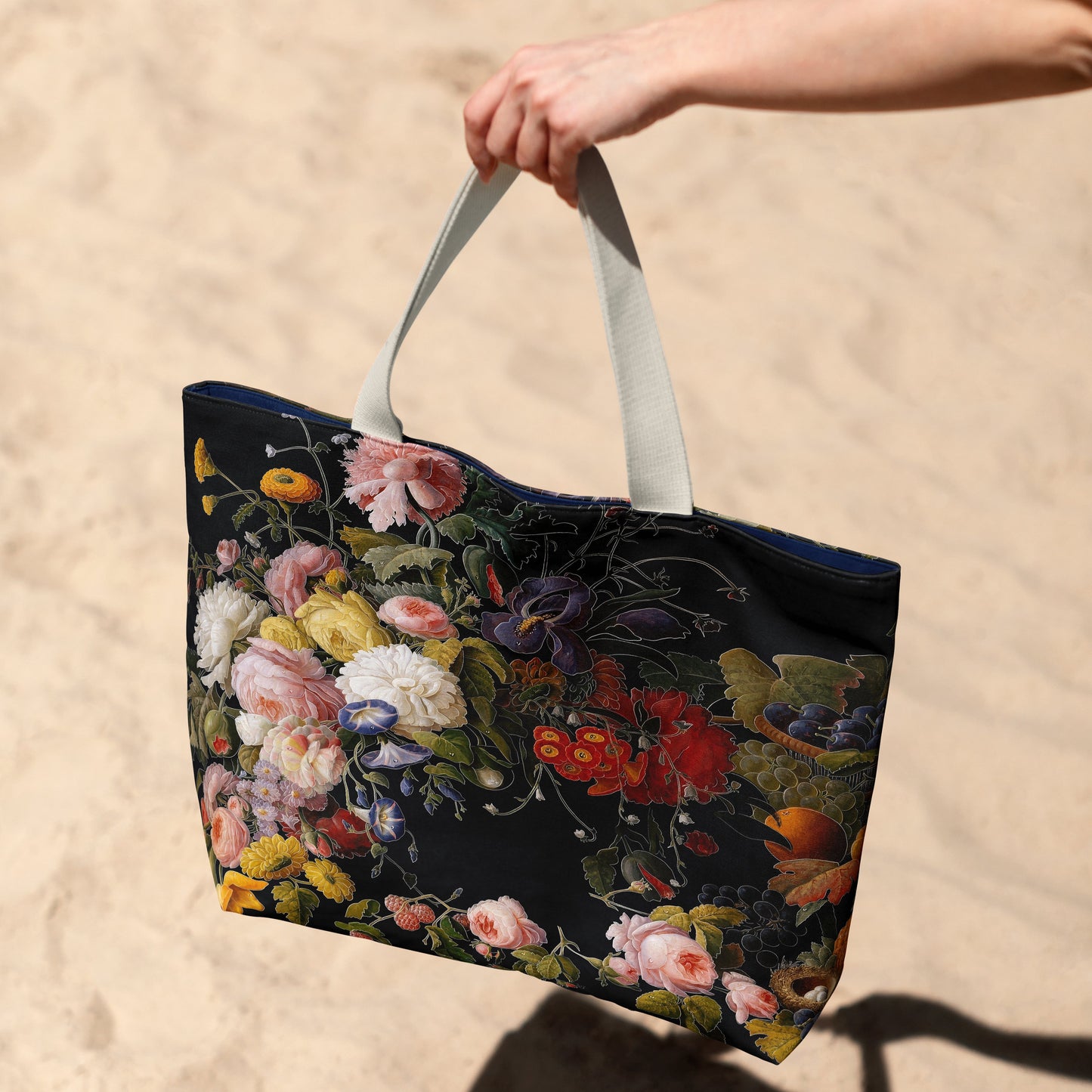 Floral tote bag held by a hand on a sandy background