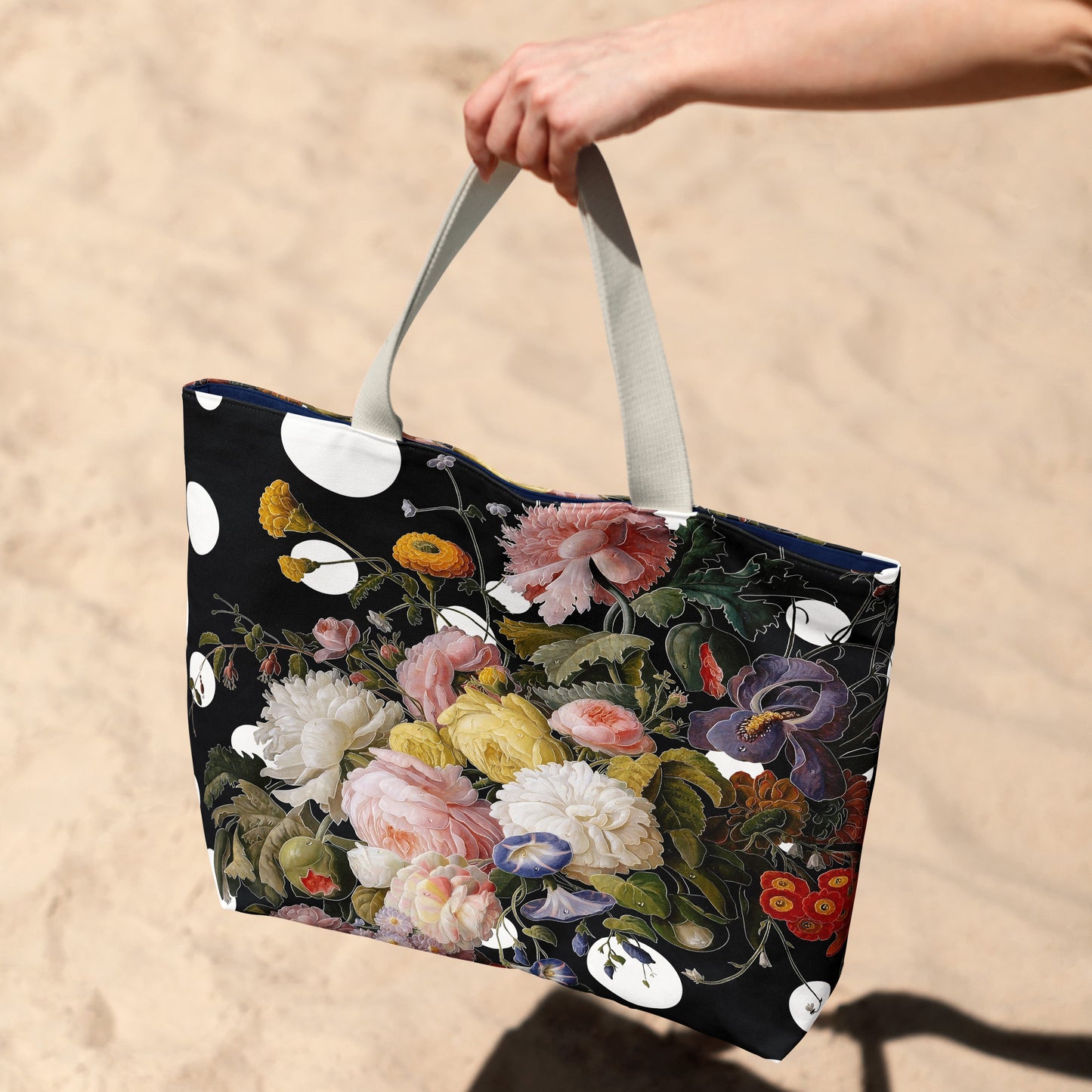 Floral-patterned tote bag held by a hand on a sandy background