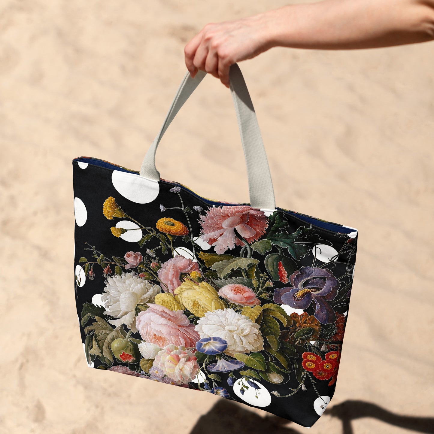 Floral-patterned tote bag held by a hand on a sandy background