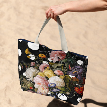 Floral-patterned tote bag held by a hand on a sandy background