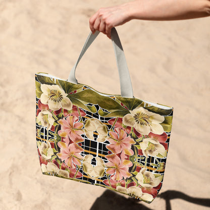 Tote bag with floral design held by a hand on a sandy background